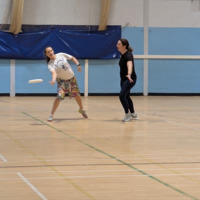 A Wyverns player releasing a forehand throw indoors while a defender marks closely