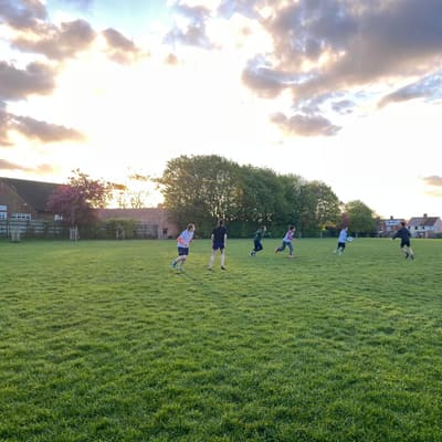 Wyverns players spread across an outdoor pitch running a point under a dramatic sunset sky